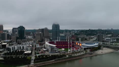 Aerial-view-away-from-the-Great-American-Ball-Park-and-the-Cincinnati-skyline,-gloomy-day-with-low-clouds-in-USA---rotating,-pull-back,-drone-shot