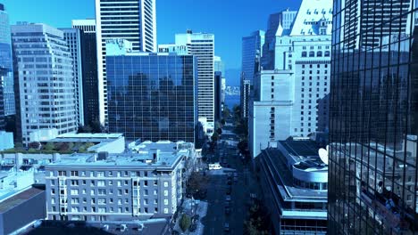 Drone-flyover-Vancouvers-Burrard-Street-towards-Robson-130-feet-above-the-ground-overlooking-hotels-office-towers-mirrored-glass-window-reflection-light-traffic-sunny-day-blue-clear-sky-green-trees1-5