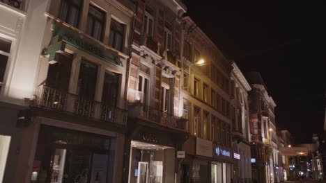 Tilt-down-of-shopping-district-in-Ghent,-Belgium-at-night