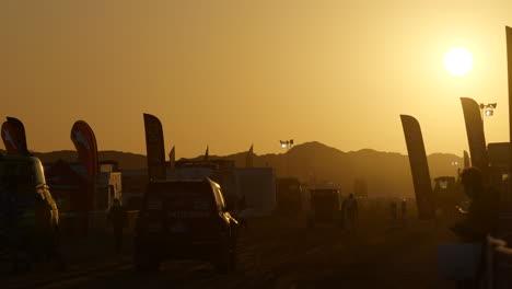 Fiery-orange-sunrise-over-the-Paris-Dakar-main-camp-with-vehicles-driving-in