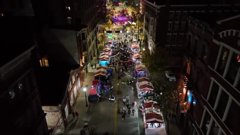Aerial-view-over-the-illuminated-East-5th-street-in-downtown-Cincinnati,-USA,-during-BLINK-the-festival-of-lights---tilt,-drone-shot
