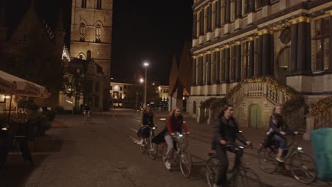 Gente-En-Bicicleta-Recorriendo-El-Centro-Histórico-De-La-Ciudad-En-Gante,-Bélgica-Por-La-Noche