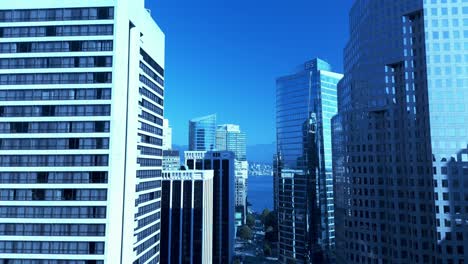 Vancouver-aerial-drone-flight-over-Burrard-street-on-a-sunny-hot-fall-day-clear-blue-sky-green-trees-calm-waterfront-across-the-North-Vancouver-shores-overlooking-hotels-offices-lush-plants-4-5