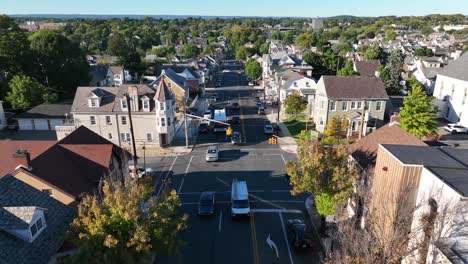 Reverse-aerial-tracking-shot-of-cars-on-road-through-historic-housing-district