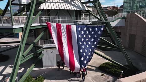 Aerial-view-around-people-raising-the-US-flag-to-the-Sunsphere-tower-in-USA---circling,-drone-shot