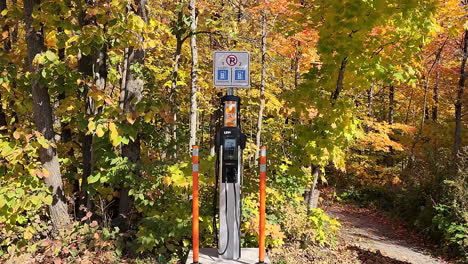 Dolly-in-on-electric-vehicle-EV-charger-in-outdoor-nature-during-fall-autumn-vibrant-color-forest-no-parking-unless-charging