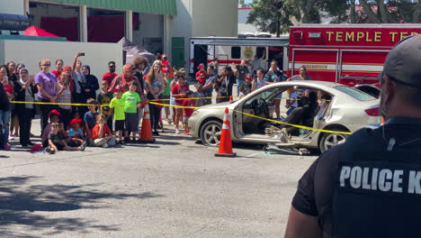 Police-officer-giving-commands-and-walking-a-police-dog-around-for-a-crowd-of-people-in-Front-of-Temple-Terrace-Fire-Station-Florida,-at-a-fire-and-safety-event