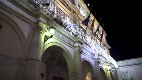 Zeitlupenaufnahme-Des-Rathauses-Casa-Consistorial-In-Medina-Sidonia-In-Cadiz-Spanien-Mit-Geschmücktem-Balkon-Für-Weihnachten-Mit-Lichterketten-Und-Weihnachtselementen-Und-Verschiedenen-Flaggen