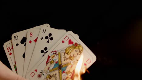 Playing-cards-held-in-one-hand-are-burned
