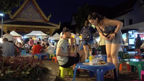 Foreigners-enjoying-street-food-at-night-market-in-Chiang-Mai,-Thailand