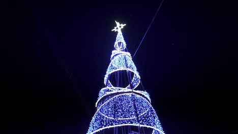 Statische-Aufnahme-Eines-Leuchtenden-Kegels,-Der-Oben-Mit-Einem-Leuchtenden-Stern-Zu-Weihnachten-In-Der-Nacht-In-Einem-Blau-weißen-Licht-Verziert-Ist