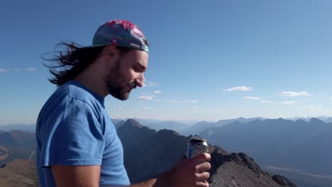 Hiker-drinking-beer-on-peak-at-Rocky-Mountain-range-Close-up-Kananaskis-Alberta-British-Columbia-border-Canada