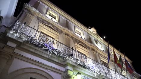 Low-angle-slow-motion-shot-of-the-city-hall-Casa-Consistorial-in-medina-sidonia-cadiz-decorated-with-christmas-elements-and-fairy-lights-and-different-country-flags