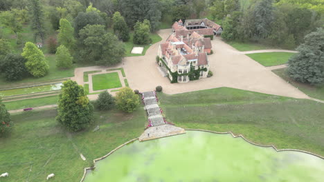 Aerial-drone-shot-orbiting-around-the-British-style-mansion-called-the-Palace-of-Las-Fraguas,-a-20th-century-historical-landmark-made-famous-by-the-film-The-Others-in-Cantabria,-Spain