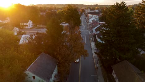 Cars-driving-on-road-in-small-American-city-during-autumn-sunset