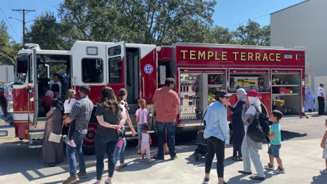 A-crowd-of-people-around-a-firefighter-rescue-truck-at-a-fire-and-safety-demonstration-in-Tampa-Bay-Florida,-looking-at-the-fire-truck,-how-it-works,-and-its-equipment
