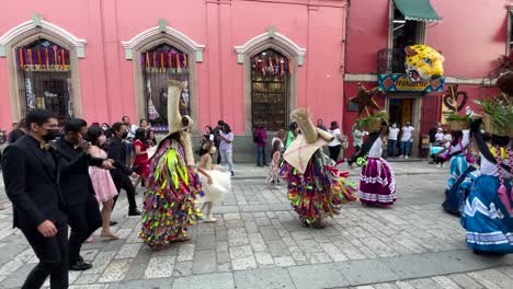 Toma-En-Cámara-Lenta-De-Una-Celebración-De-Boda-Tradicional-En-La-Ciudad-De-Oaxaca-Al-Estilo-Indígena-En-Sus-Vestidos-Tradicionales-Desfilando-Por-La-Calle-Pública