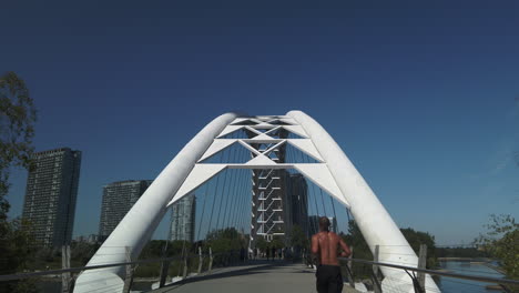 Wide-exterior-moving-shot-following-a-jogger-approaching-the-Humber-Bay-Arch-Bridge