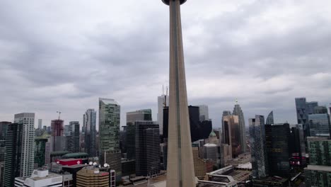 Aerial-view-in-front-of-the-CN-tower-in-downtown-Toronto,-in-cloudy-Ontario,-Canada---ascending,-drone-shot