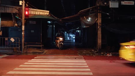 Scooter-driving-through-dark-alley-in-to-traffic-in-Bangkok,-Thailand