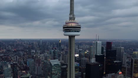 Aerial-view-around-the-CN-Tower,-dark-moody-sunset-in-Toronto,-Canada---circling,-drone-shot