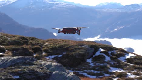 Drone-Moderno-Flotando-Frente-A-La-Cámara-Antes-De-Girar-Y-Volar-Para-Desaparecer-En-Un-Vasto-Paisaje-Montañoso---Montaña-Nesheim-En-Vaksdal-Noruega---Drone-Dji-Mavic-2-Con-Cámara-Hasselblad