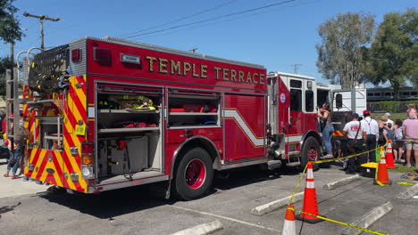 Öffentliche-Ausstellung-Im-Freien-Präsentation-Eines-Feuerwehrautos-In-Der-Feuerwache-Temple-Terrace-In-Florida,-Besucher-Nehmen-Die-Ausrüstung-Des-Feuerwehrfahrzeugs-In-Die-Hand,-Handaufnahme-Von-Hinten