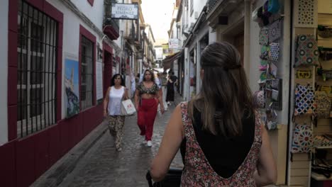 Siguiendo-A-Una-Hermosa-Madre-Caminando-Con-Un-Niño-En-Un-Cochecito-Por-Una-Calle-Angosta-En-Córdoba,-España