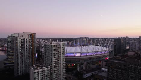 Aerial-view-in-front-of-the-BC-Place-Stadium,-colorful-evening-in-Vancouver,-Canada---ascending,-tilt,-drone-shot