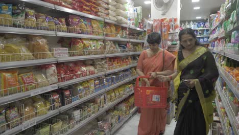 Wide-shot-of-two-middle-aged-Indian-women-shopping-for-retail-items-in-a-local-grocery-store
