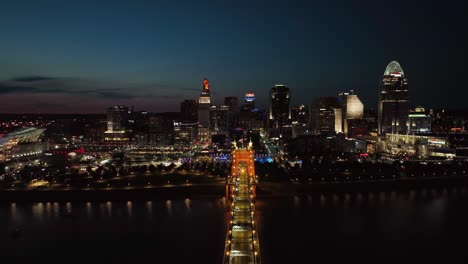 Aerial-view-over-the-Roebling-Bridge-with-Cincinnati-skyline-in-the-background,-night-in-Ohio,-USA---pull-back,-drone-shot