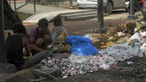 Static-shot-of-a-group-of-Asian-ragpickers-disposing-expired-medicines,-tablets,-syrups-in-the-middle-of-city's-dry-rubbish-spot