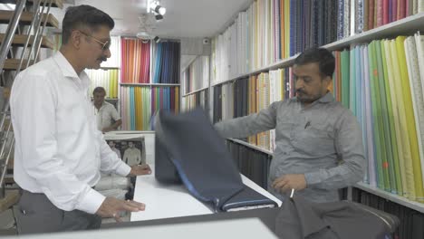 A-middle-aged-Indian-man-is-buying-raw-clothes-fabric-for-stitching-formal-wear-in-a-local-tailoring-shop