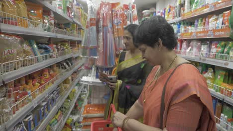 Two-middle-aged-Indian-women-shopping-for-retail-items-in-a-local-grocery-store