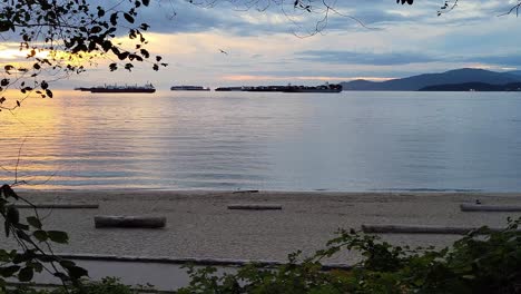 Silhouette-Von-Lastkähnen-An-Der-Englischen-Bucht-In-Der-Abenddämmerung-In-Vancouver,-Kanada,-Mit-Aktiven-Menschen,-Die-Im-Vordergrund-Joggen