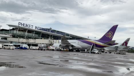 view-slowmotion-inside-the-airport-parking-bay-with-boeing-airplane-while-ground-service-cargo-operating-in-raining-day