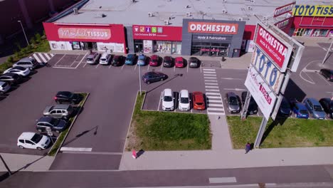 Car-pulling-into-outdoor-strip-mall-and-parking-in-lot,-Wittenheim-Alsace-France