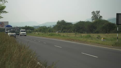 Wide-shot-of-Indian-highway-with-trucks,-cars,-bikes,-motorcycle-and-more-on-a-2-lane-highway,-Maharashtra