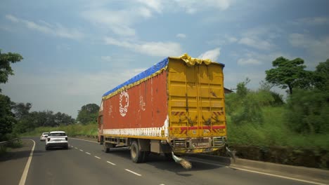 Point-of-view-shot-of-private-cars-overtaking-heavy-loaded-container-truck-on-a-highway-in-Maharashtra
