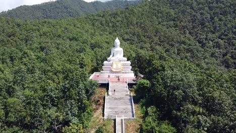 Aerial-zoom-in-of-the-big-white-Buddha-in-the-middle-of-the-mountain-range-in-Pai,-Thailand