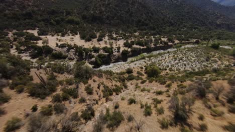 Rocky-mountains-with-bush-vegetation-in-Cajon-del-Maipo-canyon-in-Chile,-FPV-aerial-shot
