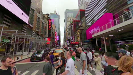 Cruzando-Una-Calle-Concurrida-En-Manhattan,-Nueva-York,-Mientras-Un-Taxi-Amarillo-Espera-En-Rojo
