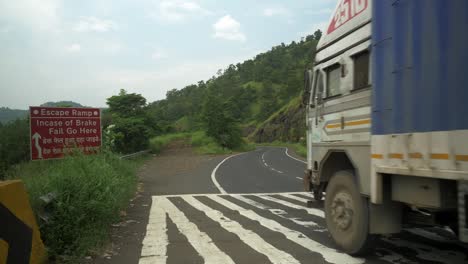 Static-shot-escape-ramp-close-to-speed-brakers-and-trucks-crossing-through-the-road-surrounded-by-mountain