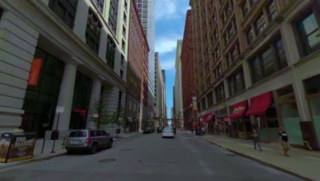 Driving-the-last-mile-of-Route-66-in-downtown-Chicago-towards-the-end-sign-between-tall-buildings-almost-closing-the-sky