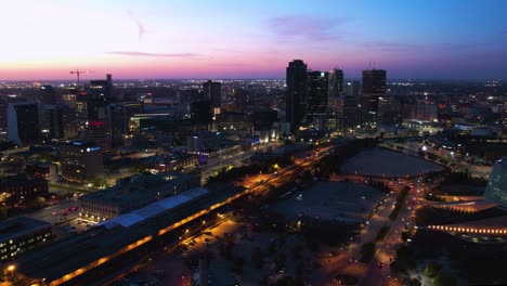 Drone-hyperlapse-overlooking-the-illuminated-city-center-of-Winnipeg,-dusk-in-Canada