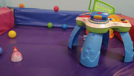 Kunststoff-Spieltisch,-Puppen-Und-Spielzeug-Im-Bunten-Schaumstoffbereich-Und-Schutzmatten-Für-Kinder-Des-öffentlichen-Kinderfreizeitzentrums,-Rolling-Left-Shot,-Ordenes,-Galizien,-Spanien