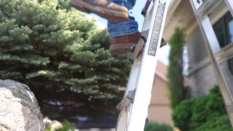 Man-climbs-a-ladder-on-a-job-site-to-repair-a-roof