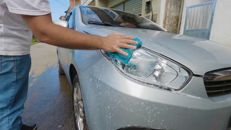 Angra-dos-Reis,-Rio-de-Janeiro,-Brazil---October-31,-2022-Washing-gray-car-with-soap-and-cloth