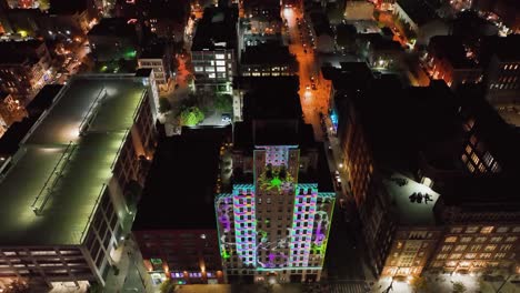 Aerial-view-of-LED-art-upscale,-Illuminated-on-a-building-wall,-at-BLINK-festival-in-Cincinnati,-Ohio,-USA---reverse,-tilt,-drone-shot