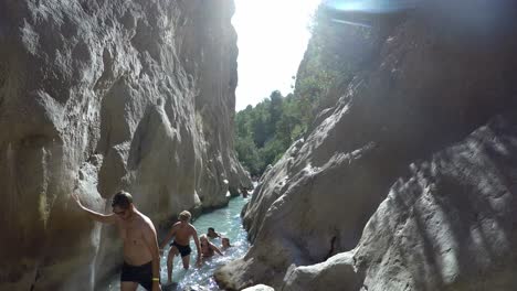 People-exploring-water-stream-canyon-passage-from-mountain-natural-spring-water-at-Fonts-de-L'Algar,-Alicante,-Spain